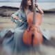 Woman with a nostalgic look playing cello on a sea shore in sunrise sc... (thumbnail)