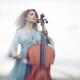 Young woman thoughtfully playing cello in a bright sunrise outdoor sce... (thumbnail)