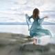 Young woman in a long dress running towards sea shore Rear view... (thumbnail)