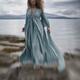 Woman in a long dress walking along the sea shore in a dramatic stormy... (thumbnail)