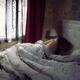 Woman lying asleep in bed in the morning covered with a blanket in a b... (thumbnail)