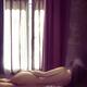 Woman lying nude on a bed er back lit with light from a window... (thumbnail)