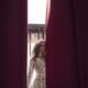 Sexy woman in lace nightgown standing by the window behind a curtain w... (thumbnail)