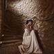 Woman in a long dress sitting on stone steps of a spiral staircase of... (thumbnail)
