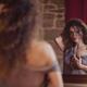 Young woman undressing in front of a mirror with a thoughtful look on... (thumbnail)