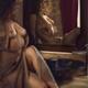 Sexy young woman sitting topless by the mirror in unbuttoned dress rev... (thumbnail)