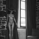 Sexy woman in a hat standing naked by a window curtain Black and white... (thumbnail)