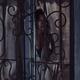 Woman face looking outside through a window behind grates at night... (thumbnail)