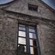 Woman face behind a closed window lit from inside of an old stone hous... (thumbnail)