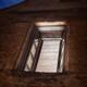 Open window of an old stone house illuminated from inside at night art... (thumbnail)