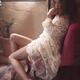 Young woman in white nightgown sitting in a chair by a window with a t... (thumbnail)