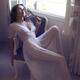 Woman in white nightgown sitting by an open window in countryside hous... (thumbnail)