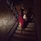 Woman in red dress running away down the staircase of an old house... (thumbnail)