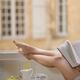 Legs of a woman reading a book by open window with French breakfast of... (thumbnail)
