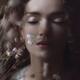 Beautiful tranquil woman face with closed eyes behind wild flowers dre... (thumbnail)