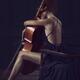Woman sitting thoughtfully with her arms around a cello in elegant dre... (thumbnail)