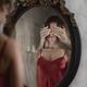 Sexy woman in red nightgown reflecting in a mirror with male hands cov... (thumbnail)