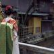 Maiko young Geisha apprentice in a red kimono with long obi standing o... (thumbnail)