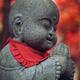 Cute Baby Buddha with a fallen maple leaf on his head stone statue in... (thumbnail)