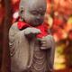 Baby Buddha cute stone statue in beautiful red autumn scenery... (thumbnail)