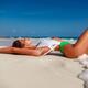 Beautiful sexy sun tanned woman in fashion swimsuit lying on white san... (thumbnail)