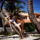 Sexy blond woman in bikini swimsuit sunbathing on a trunk of palm tree... (thumbnail)