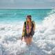 Pretty blond woman bathing in bikini swimsuit and swim vest coming out... (thumbnail)