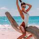 Sun-tanned exotic woman in swimsuit at a sandy sunny beach sitting on... (thumbnail)
