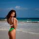 Sexy sun-tanned woman on a sandy beach shore in a swimsuit looking ove... (thumbnail)