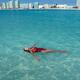 Woman in red swimsuit lying in clear blue water of Caribbean Sea with... (thumbnail)