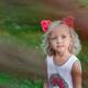 Cute little girl with pink flowers in her blond hair with a thoughtful... (thumbnail)