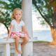 Portrait of a cute little blond girl sitting on wooden railings at the... (thumbnail)