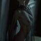 Nude woman leaning against a wall in a dark room her naked body covere... (thumbnail)