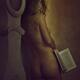 Woman in glasses standing naked holding a book in her hand in a dark h... (thumbnail)