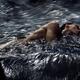Man lying half submerged in turbulent water of a river stream in drama... (thumbnail)