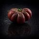 Wet dark red organic heirloom tomato Black Krim on black background wi... (thumbnail)