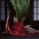 Asian woman in red kimono drinking tea half dressed by open shoji door... (thumbnail)