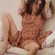 Sexy young woman in bohemian dress sitting on a white sofa in a sensua... (thumbnail)