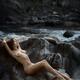 Beautiful nude woman lying on rocks by a river in nature scenery Fine... (thumbnail)