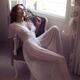Woman in white nightgown sitting by an open window in countryside hous... (thumbnail)