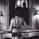 Woman back in sexy lingerie by mantelpiece with a shadowy dark silhoue... (thumbnail)