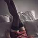 Woman lying on bed in sexy silk red nightgown with her long legs in st... (thumbnail)