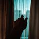 Male hand reaching towards the window from darkness of a house... (thumbnail)