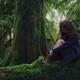 Nostalgic tranquil moody nature scenery of a woman sitting on mossy tr... (thumbnail)
