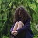 Woman with long curly hair and dreamy expression sitting in tranquil m... (thumbnail)