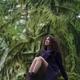 Woman with dreamy expression sitting on mossy tree trunk in purple coa... (thumbnail)