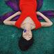 Surreal portrait of an extravagant lady in red dress lying on blue gra... (thumbnail)