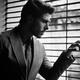 Handsome young man in classic gray suit looking out through window bli... (thumbnail)