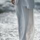 Woman in white summer clothes standing on a pebble shore with fresh co... (thumbnail)