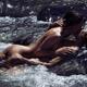 Sensual couple in an embrace lying kissing naked in turbulent water of a mountain river